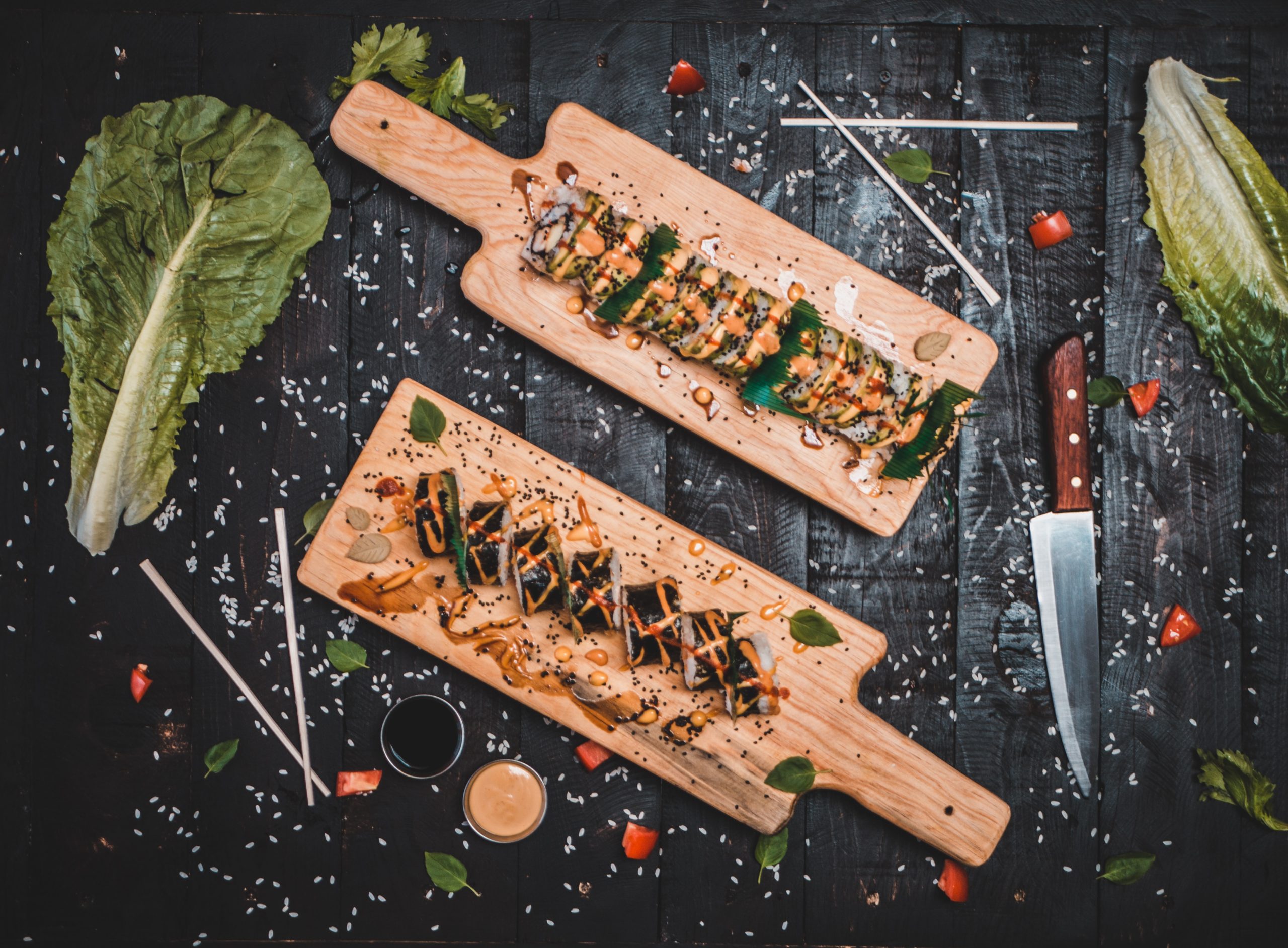 Two rolls of sushi on two chopping boards